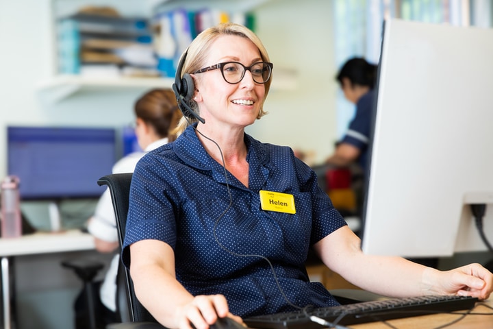 A staff member using the computer wearing a headset
