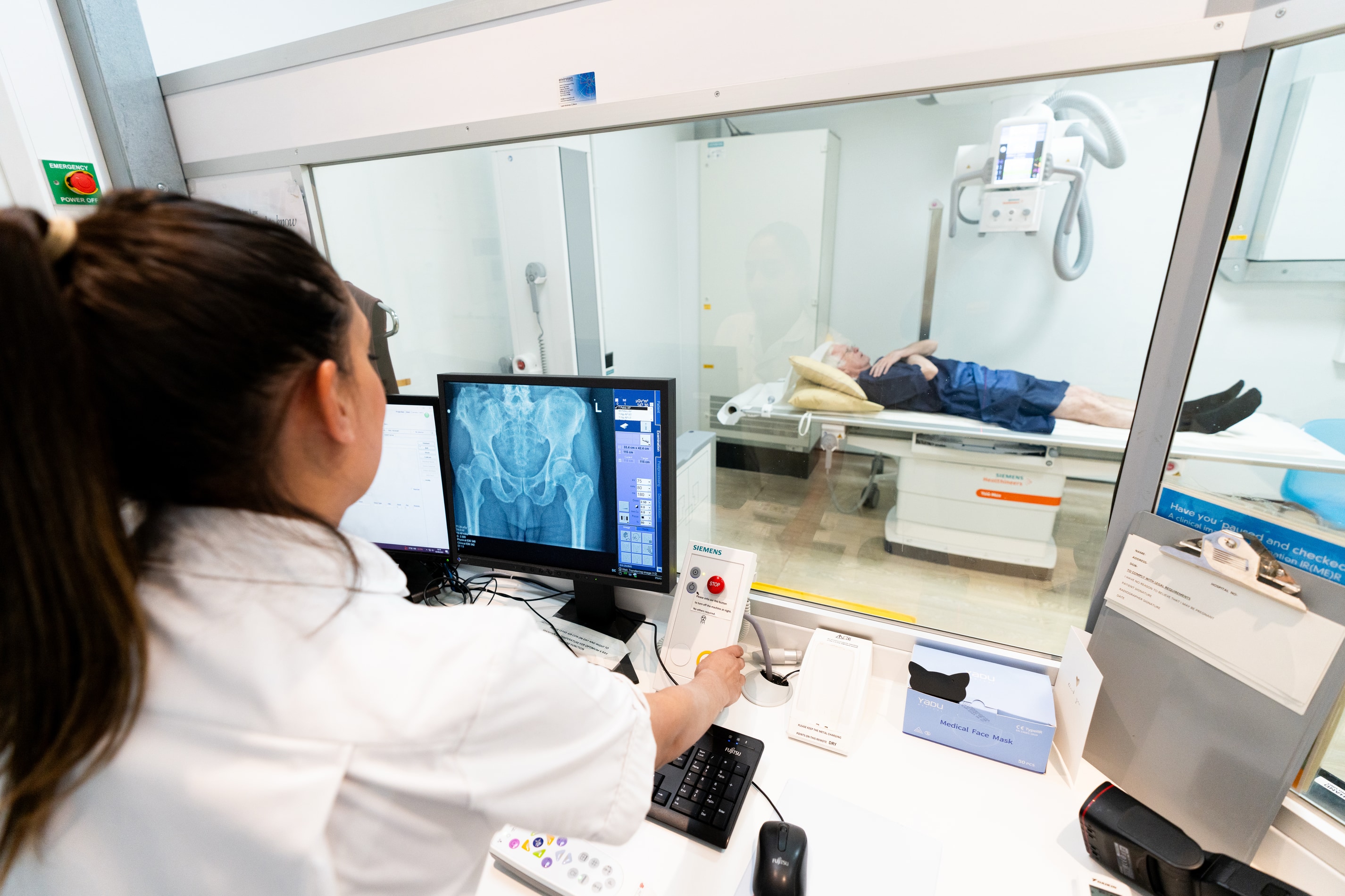 A man having an xray with a nurse looking at the images on a screen